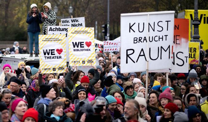 Viele Menschen protestieren im Winter mit bunten Schildern und Slogans gegen Kürzungen in der Kultur.